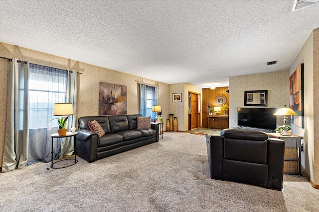 living area featuring visible vents, carpet floors, and a healthy amount of sunlight