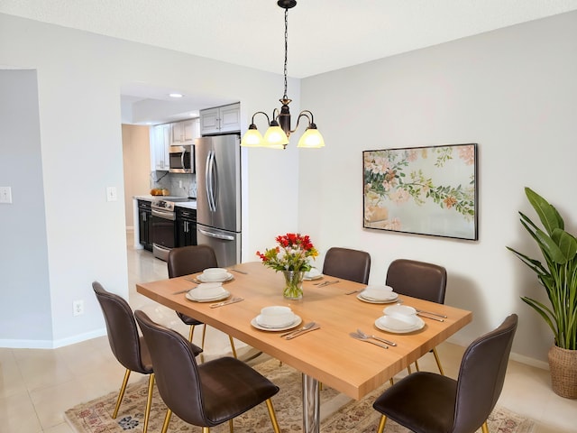 dining space featuring light tile patterned floors, baseboards, and a notable chandelier