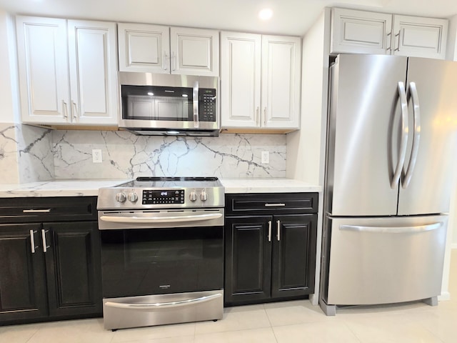 kitchen with appliances with stainless steel finishes, backsplash, white cabinetry, and dark cabinets