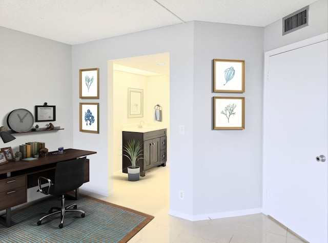 office featuring tile patterned flooring, visible vents, a sink, and baseboards