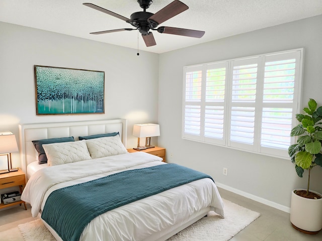 bedroom with a ceiling fan, a textured ceiling, and baseboards