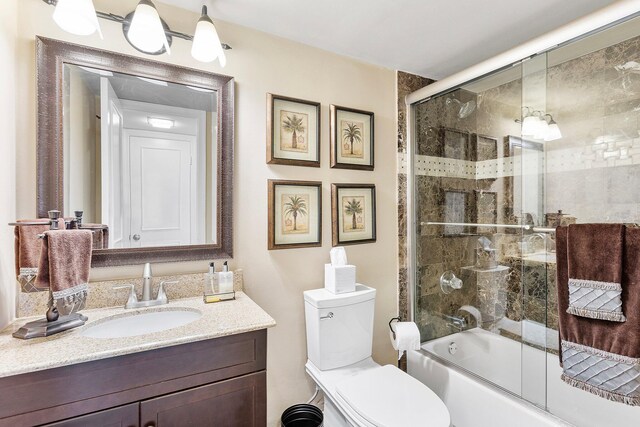 bathroom with toilet, shower / bath combination with glass door, and vanity