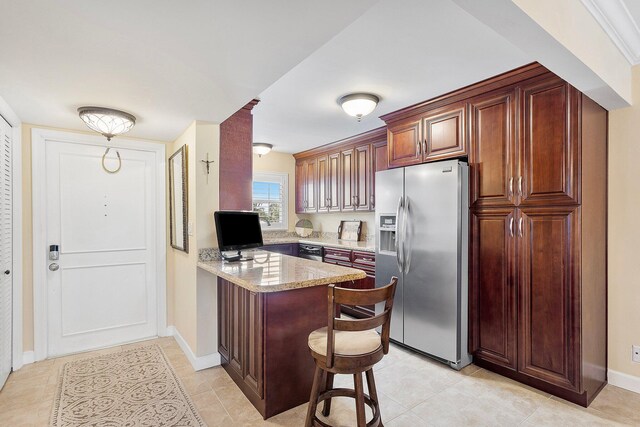 kitchen with baseboards, a breakfast bar area, a peninsula, light stone countertops, and stainless steel refrigerator with ice dispenser