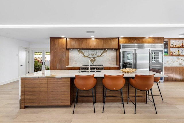 kitchen featuring visible vents, tasteful backsplash, built in fridge, french doors, and brown cabinetry