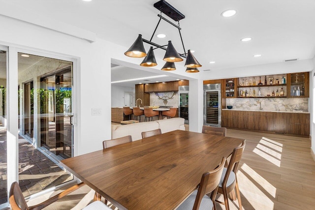 dining space with beverage cooler, visible vents, recessed lighting, a bar, and light wood-style floors