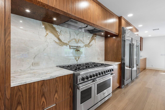 kitchen featuring modern cabinets, light wood-type flooring, high end appliances, and brown cabinetry