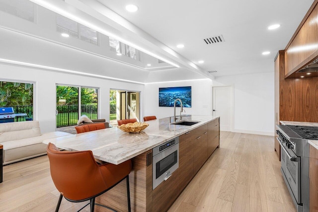 kitchen with double oven range, visible vents, a sink, a large island, and open floor plan