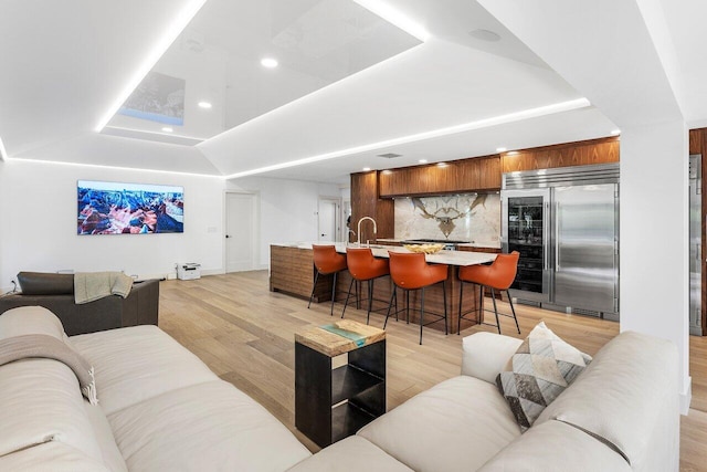 living room featuring recessed lighting, light wood-style flooring, and a tray ceiling