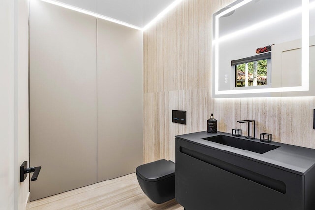 half bathroom featuring toilet, vanity, and wood finished floors