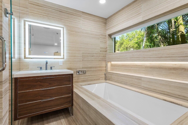 full bath with an enclosed shower, a garden tub, tile walls, and vanity