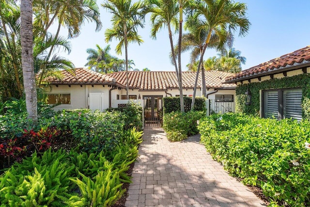 mediterranean / spanish-style home with stucco siding, a tiled roof, french doors, and a gate