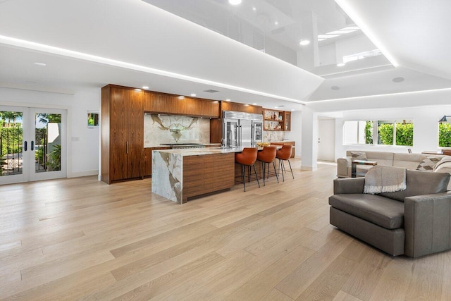 living area featuring light wood-style flooring, french doors, baseboards, and a towering ceiling