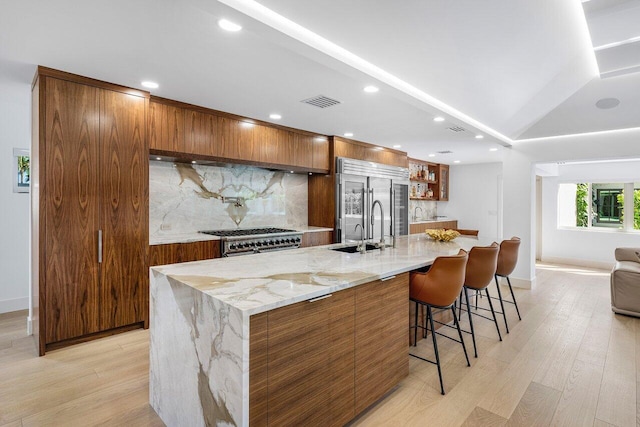 kitchen featuring brown cabinetry, modern cabinets, tasteful backsplash, and a sink