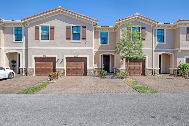 multi unit property with stone siding, driveway, and stucco siding