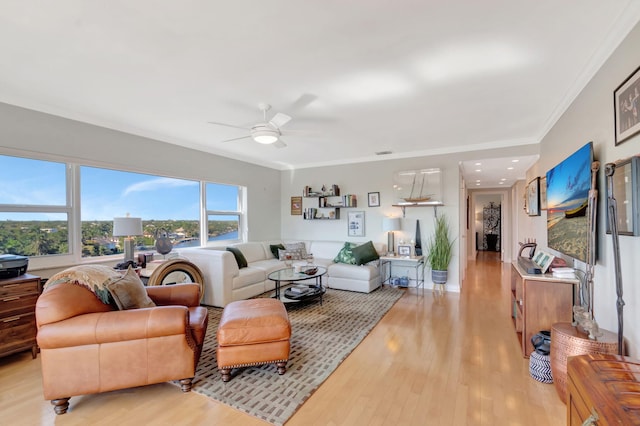 living area featuring visible vents, light wood-style floors, a ceiling fan, and crown molding