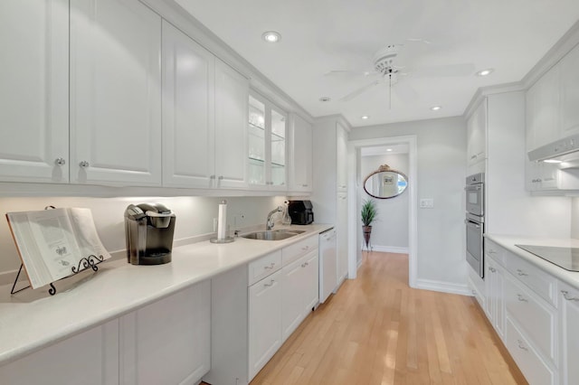 kitchen featuring black electric stovetop, a sink, white cabinets, dishwasher, and light wood finished floors