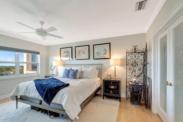 bedroom featuring light wood finished floors, visible vents, ornamental molding, a ceiling fan, and baseboards