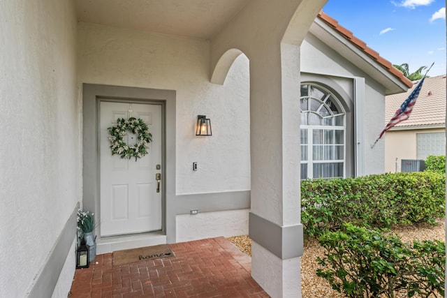 entrance to property with a tiled roof and stucco siding