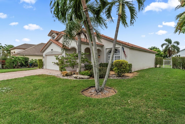 mediterranean / spanish-style house with a garage, fence, decorative driveway, a front lawn, and stucco siding