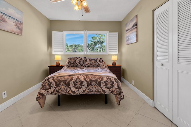 bedroom with a ceiling fan, light tile patterned flooring, baseboards, and a closet