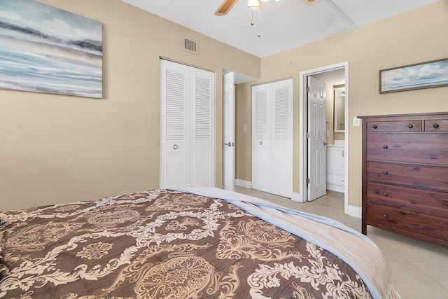 tiled bedroom with visible vents, connected bathroom, baseboards, ceiling fan, and a closet