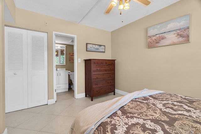 bedroom featuring baseboards, light tile patterned floors, a closet, a textured ceiling, and a ceiling fan