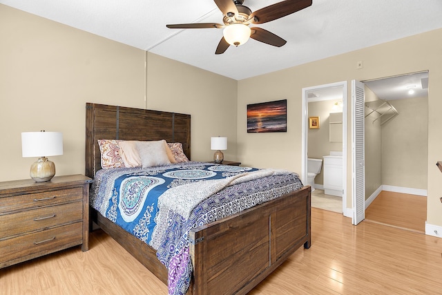 bedroom with ensuite bath, light wood-style flooring, a ceiling fan, and baseboards
