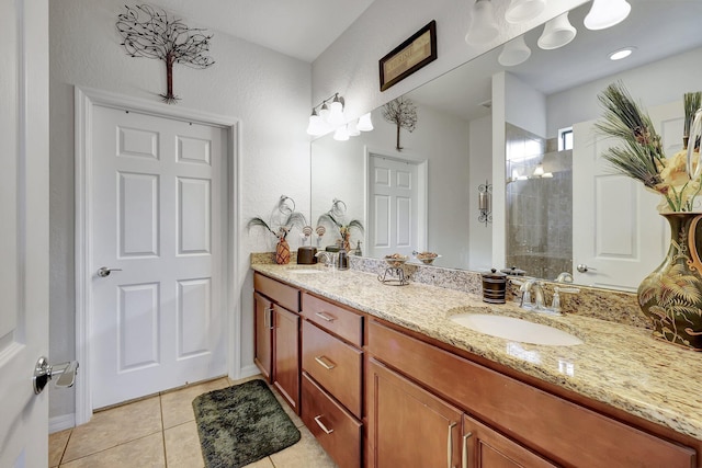 full bath with double vanity, tile patterned flooring, a tile shower, and a sink