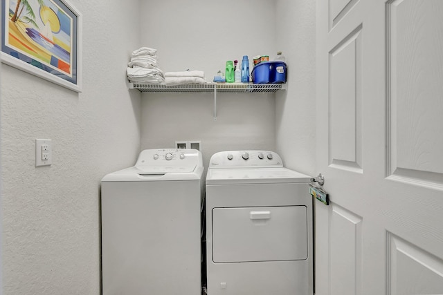 laundry area featuring laundry area, a textured wall, and washing machine and clothes dryer