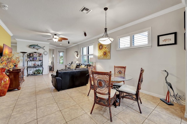 dining room featuring ceiling fan, light tile patterned flooring, visible vents, baseboards, and crown molding