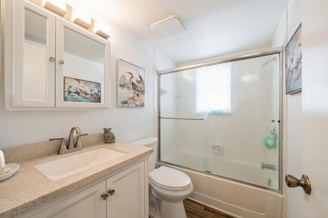 bathroom featuring toilet, shower / bath combination with glass door, wood finished floors, and vanity