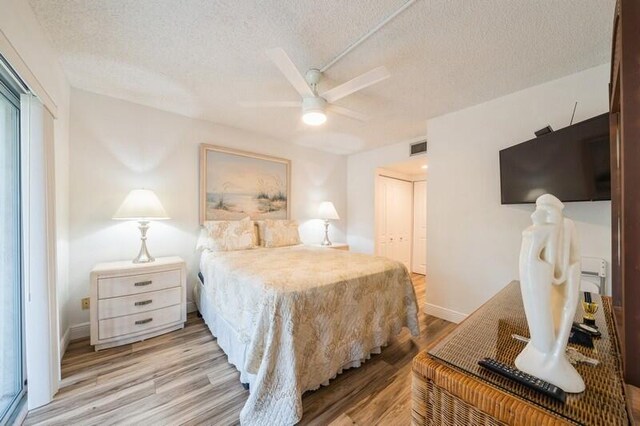 bedroom with light wood-type flooring, a textured ceiling, visible vents, and a closet