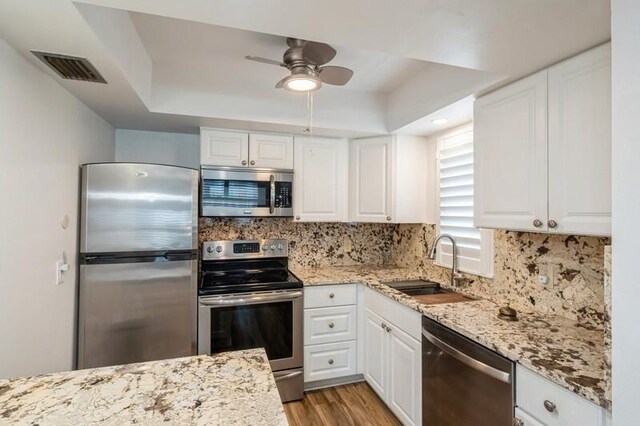 kitchen featuring appliances with stainless steel finishes, white cabinetry, a sink, and backsplash