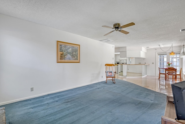 unfurnished room featuring a ceiling fan, light colored carpet, visible vents, and a textured ceiling