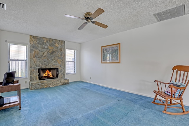 living area with visible vents, carpet, a fireplace, and a textured ceiling