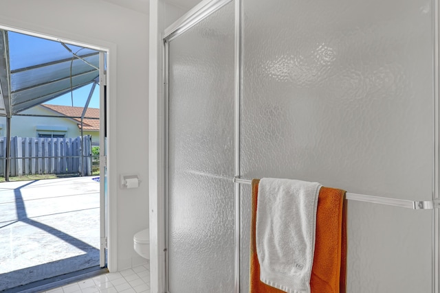 bathroom featuring tile patterned floors, toilet, and a shower with door