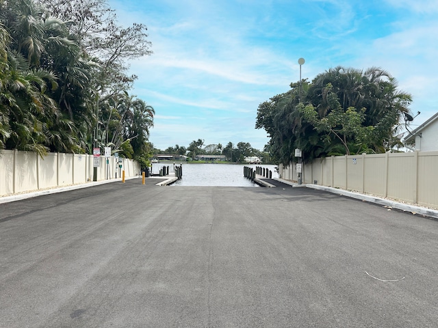 view of road featuring curbs, a water view, and street lighting