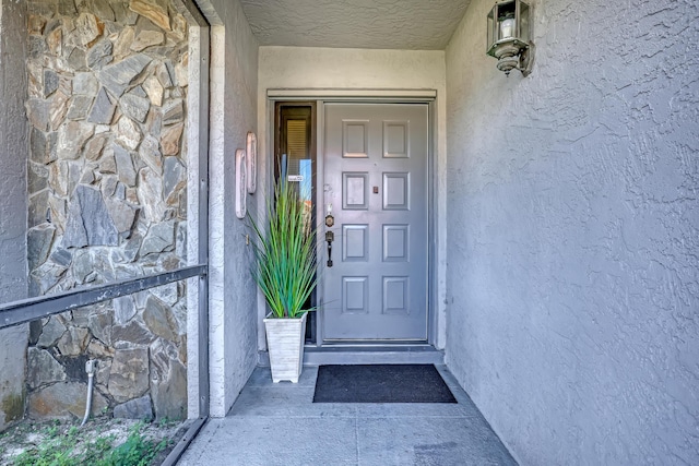 entrance to property featuring stone siding and stucco siding