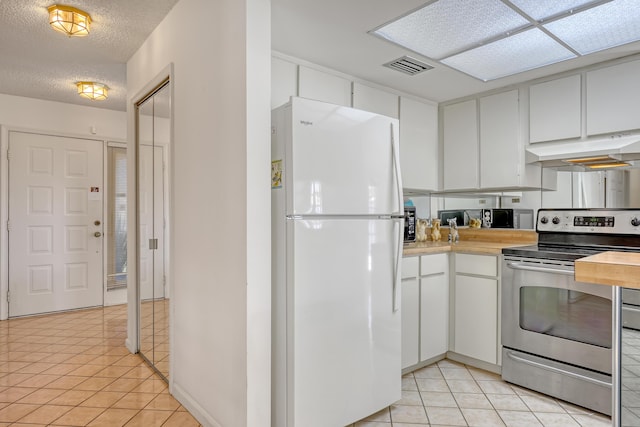 kitchen featuring stainless steel electric range oven, visible vents, freestanding refrigerator, under cabinet range hood, and a textured ceiling