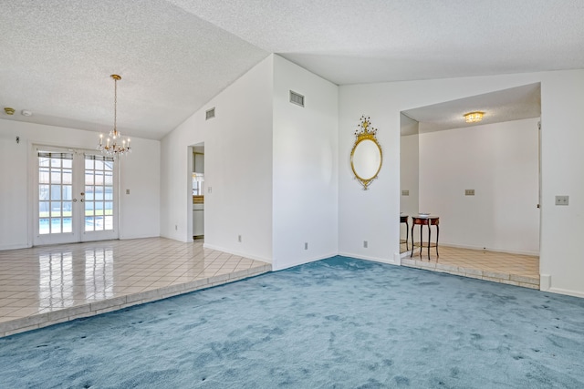 tiled spare room with visible vents, a textured ceiling, french doors, carpet flooring, and vaulted ceiling