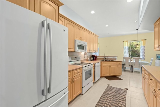 kitchen with white appliances, light tile patterned floors, a peninsula, light brown cabinets, and a sink