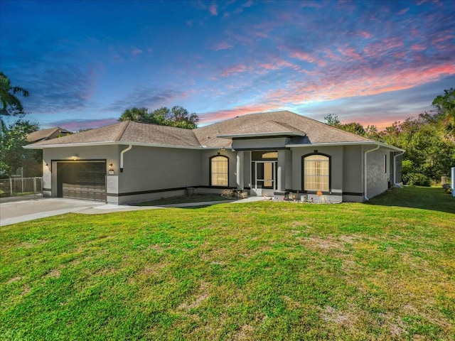 view of front of house with a yard, concrete driveway, an attached garage, and stucco siding