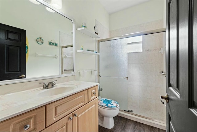 bathroom with a stall shower, vanity, toilet, and wood finished floors