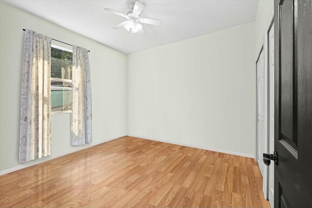 empty room featuring a ceiling fan, light wood-type flooring, and baseboards