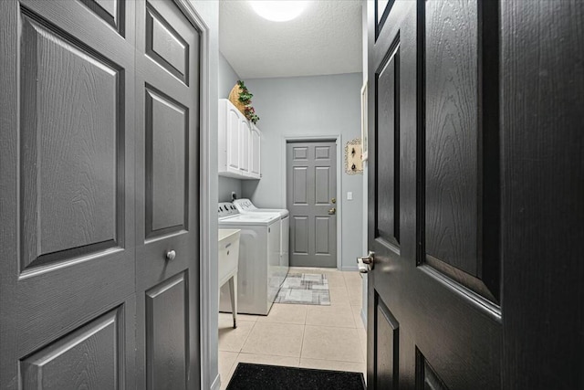 laundry area featuring cabinet space, washer and clothes dryer, a textured ceiling, and light tile patterned floors