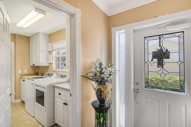 laundry room featuring cabinet space, light tile patterned floors, baseboards, washer and clothes dryer, and ornamental molding