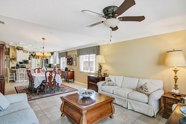 living area with crown molding, light tile patterned floors, visible vents, a ceiling fan, and baseboards