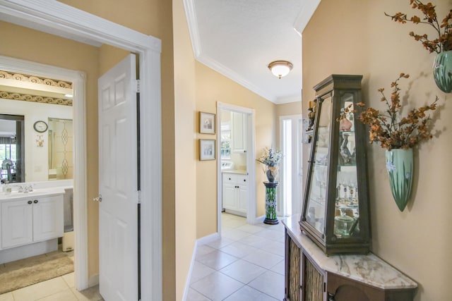 hallway featuring light tile patterned floors, ornamental molding, a sink, and baseboards