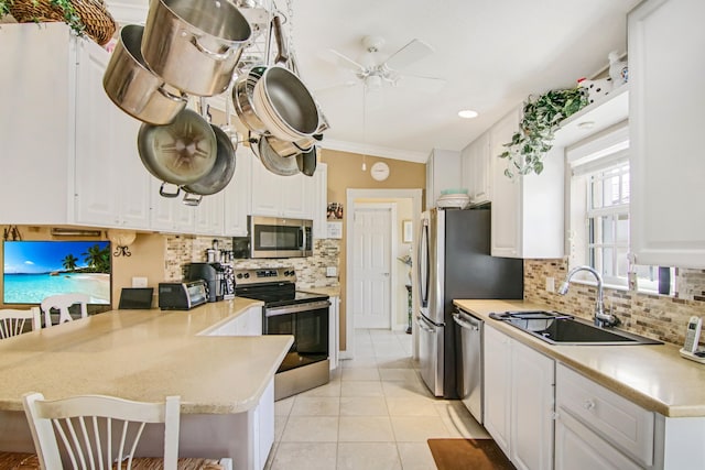 kitchen featuring light countertops, appliances with stainless steel finishes, white cabinets, a sink, and a peninsula