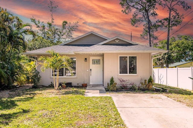 bungalow featuring a shingled roof, fence, and a front yard